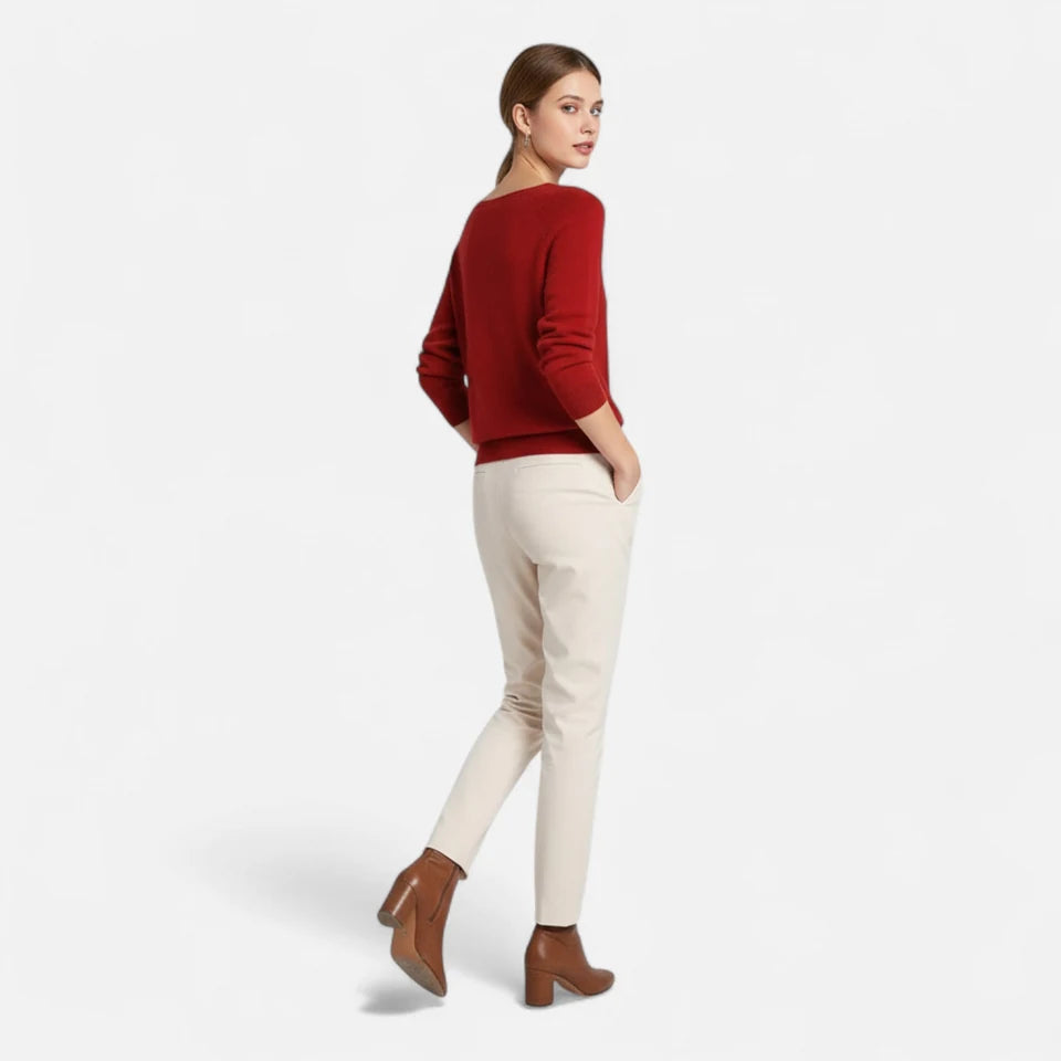 A woman wearing a red top and light trousers.